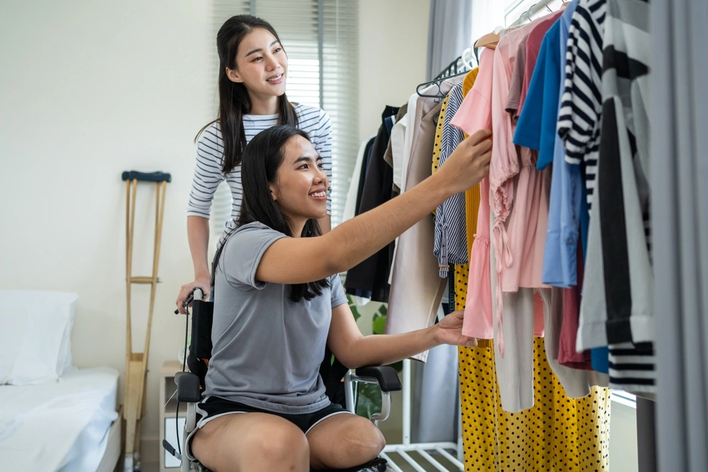 disabled girl on wheelchair picking clothes with her caretaker